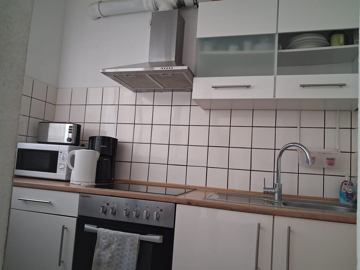 Küchenzeile der Gemeinschaftsküche mit Ceranfeld, Backofen, Mikrowelle, Wasserkocher und Spüle